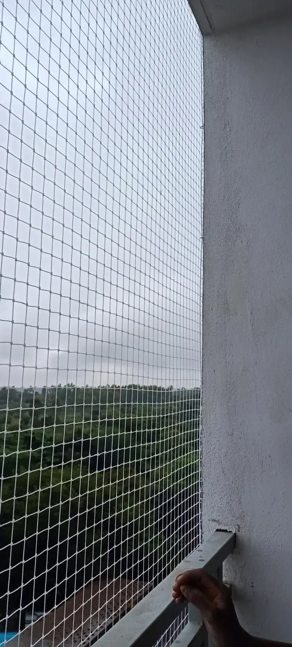 Installer checking the lower edge of a freshly fitted balcony pigeon net