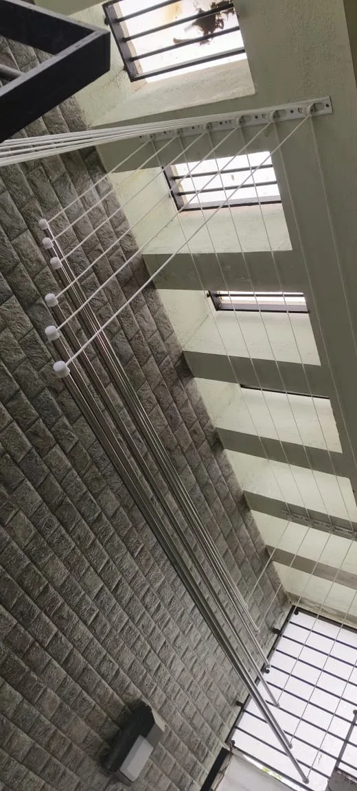 Ceiling drying rack rails running along a stone-clad open utility shaft