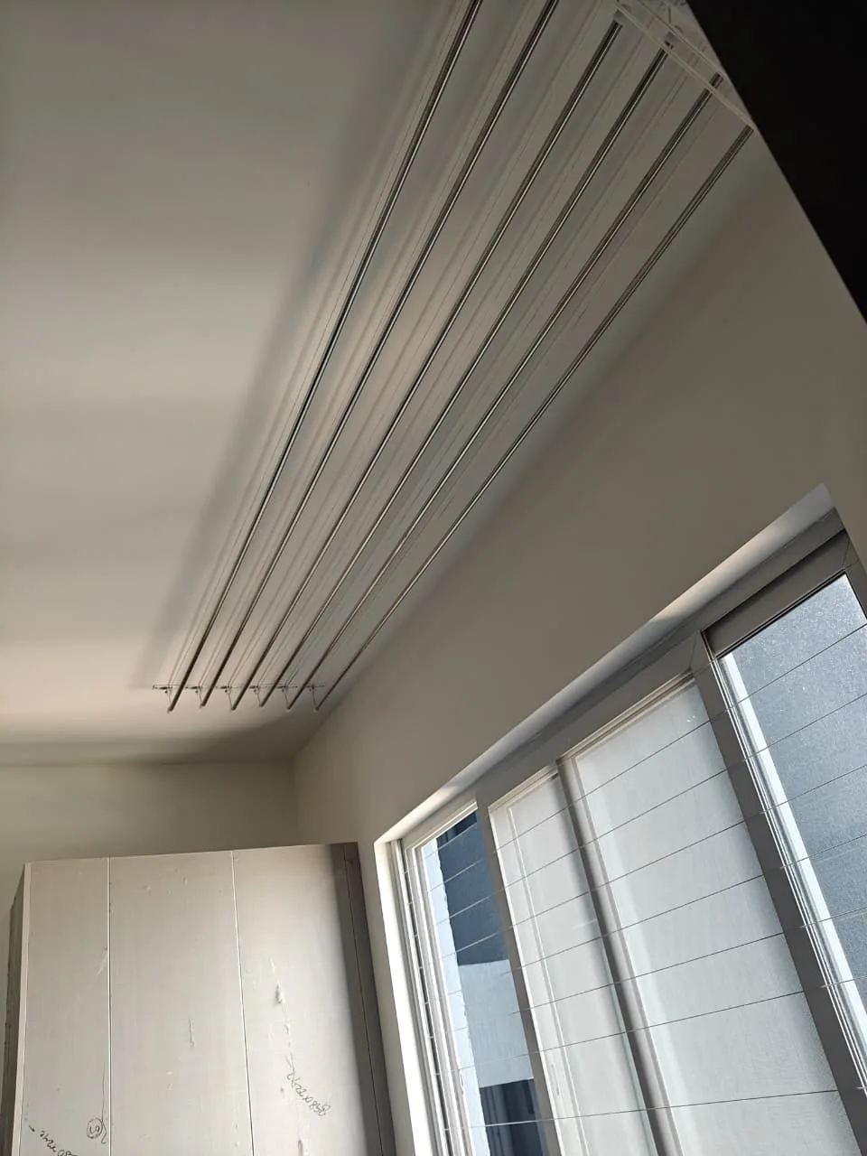 Slim ceiling cloth hanger rails installed above a bedroom window
