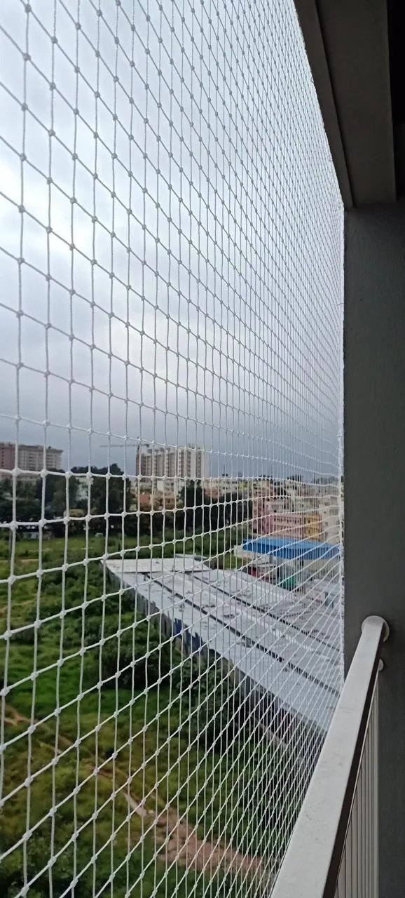 Pigeon net stretched taut along an apartment balcony railing on a cloudy day