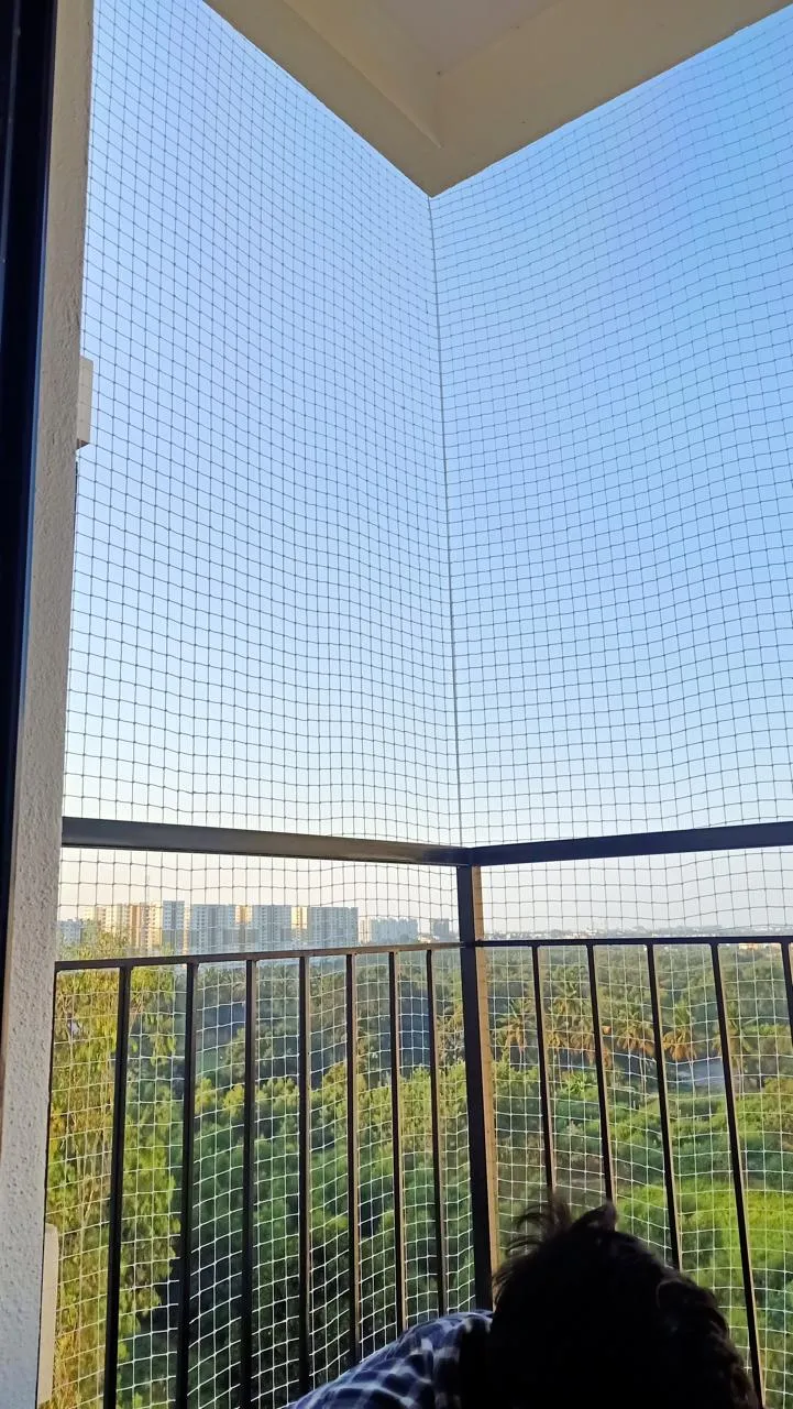 Corner balcony enclosed with a fine bird net looking out over treetops
