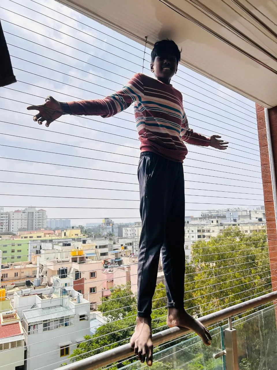 Child leaning safely against horizontal invisible grill cables on a Bangalore balcony