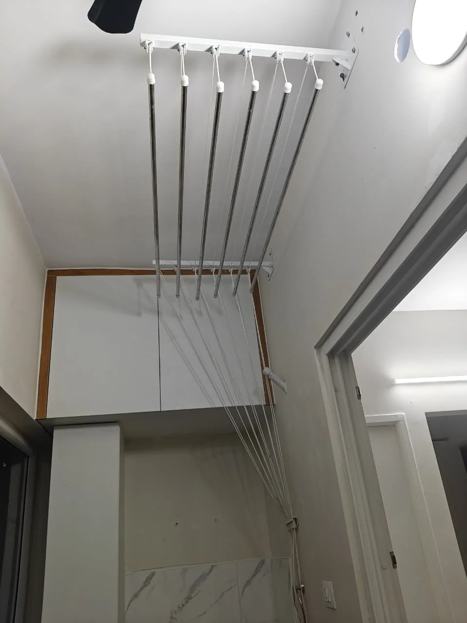Ceiling cloth hanger rails hung from a bracket in a laundry corner