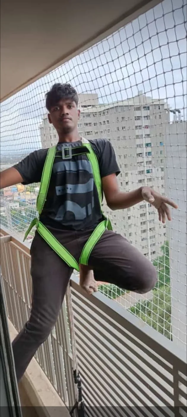 Technician in a safety harness checking a newly installed balcony safety net