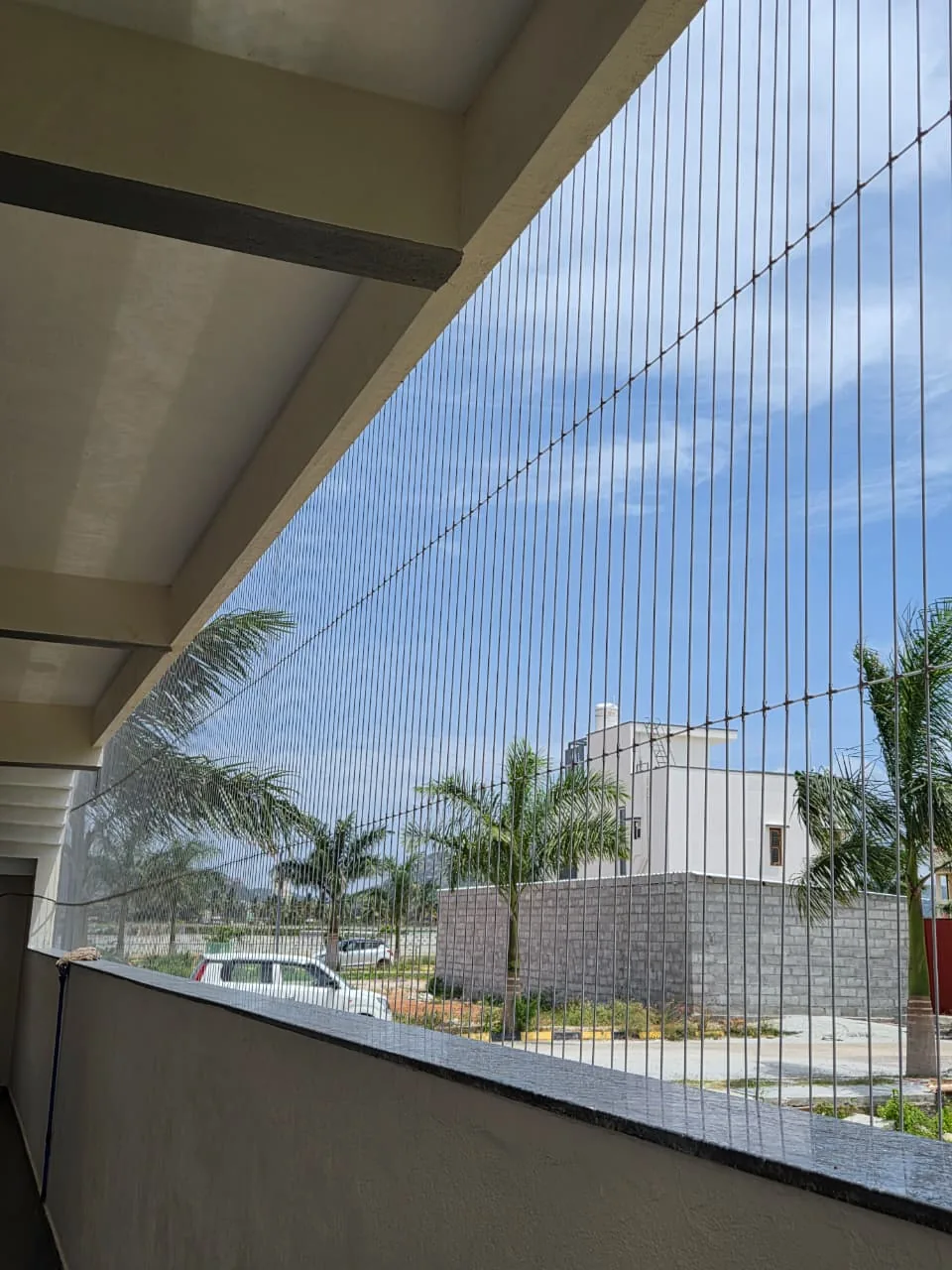 Stainless steel invisible grill cables along an open balcony with garden view