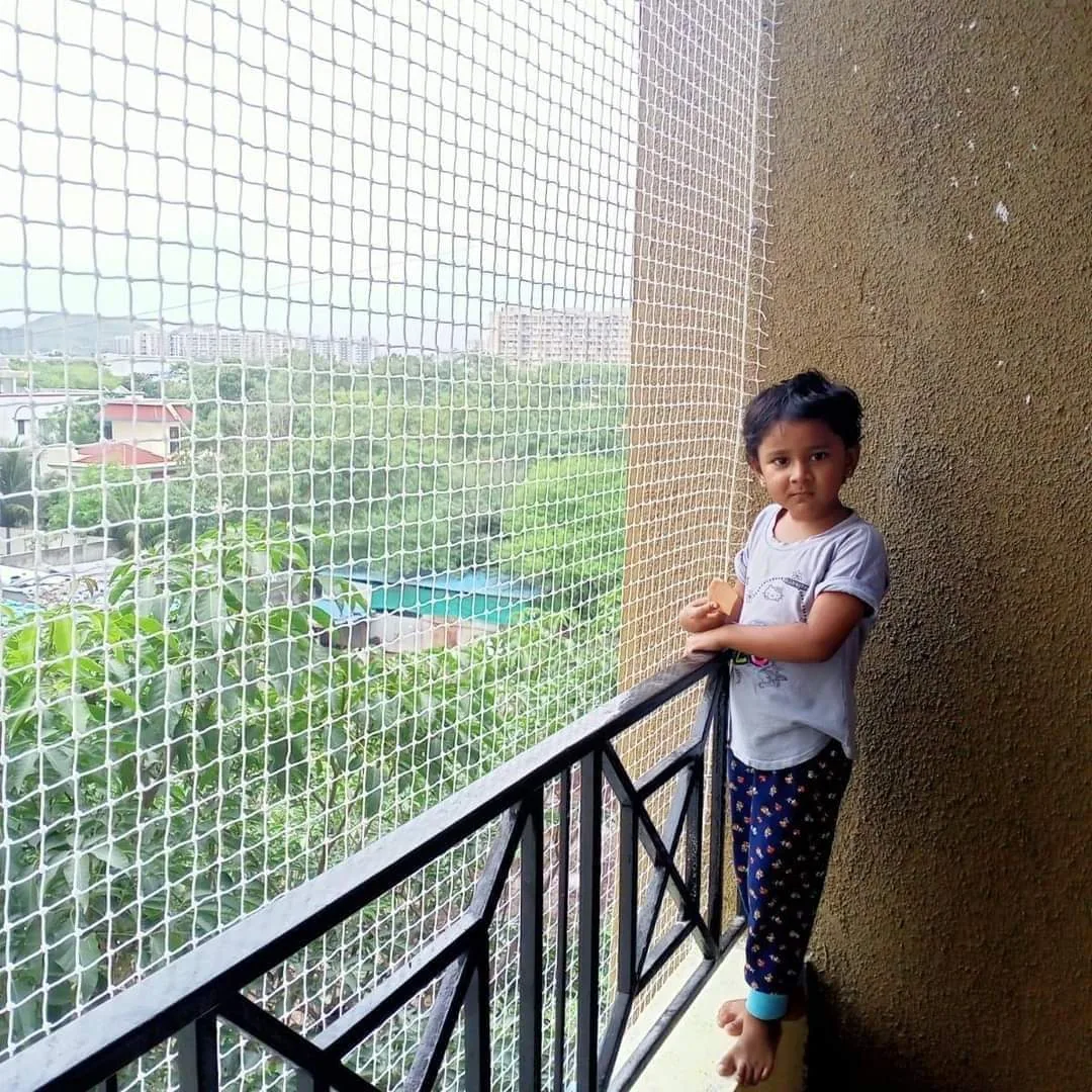 Young girl standing on a balcony secured with a white children safety net