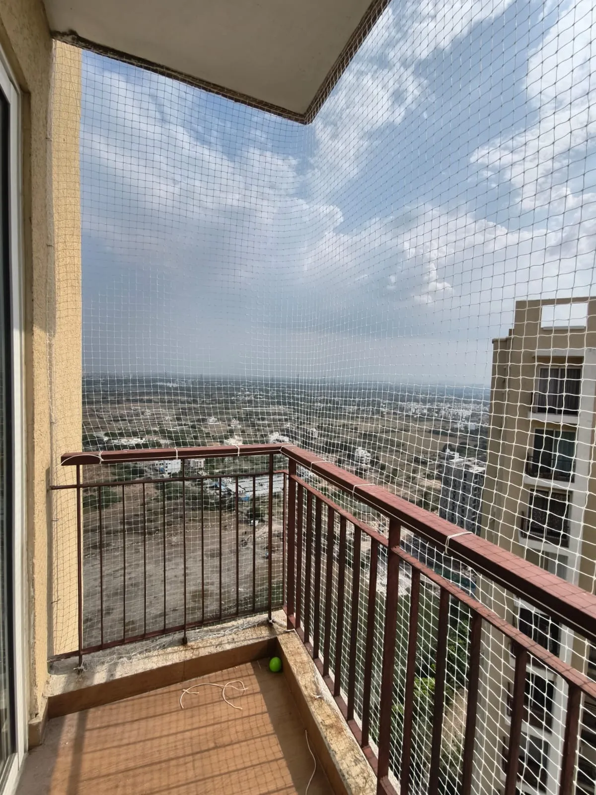 Corner balcony fully enclosed with a pigeon net overlooking the city