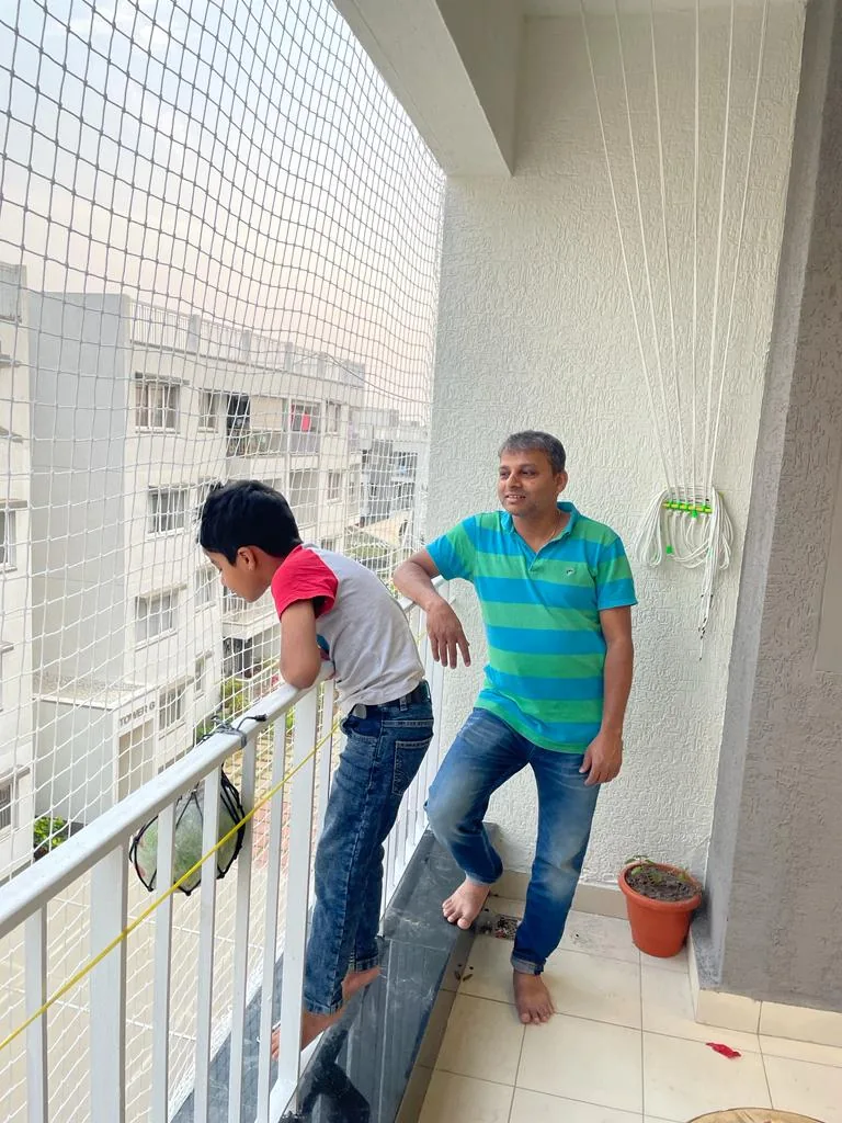 Father and son on an apartment balcony fitted with a children safety net and cloth hanger
