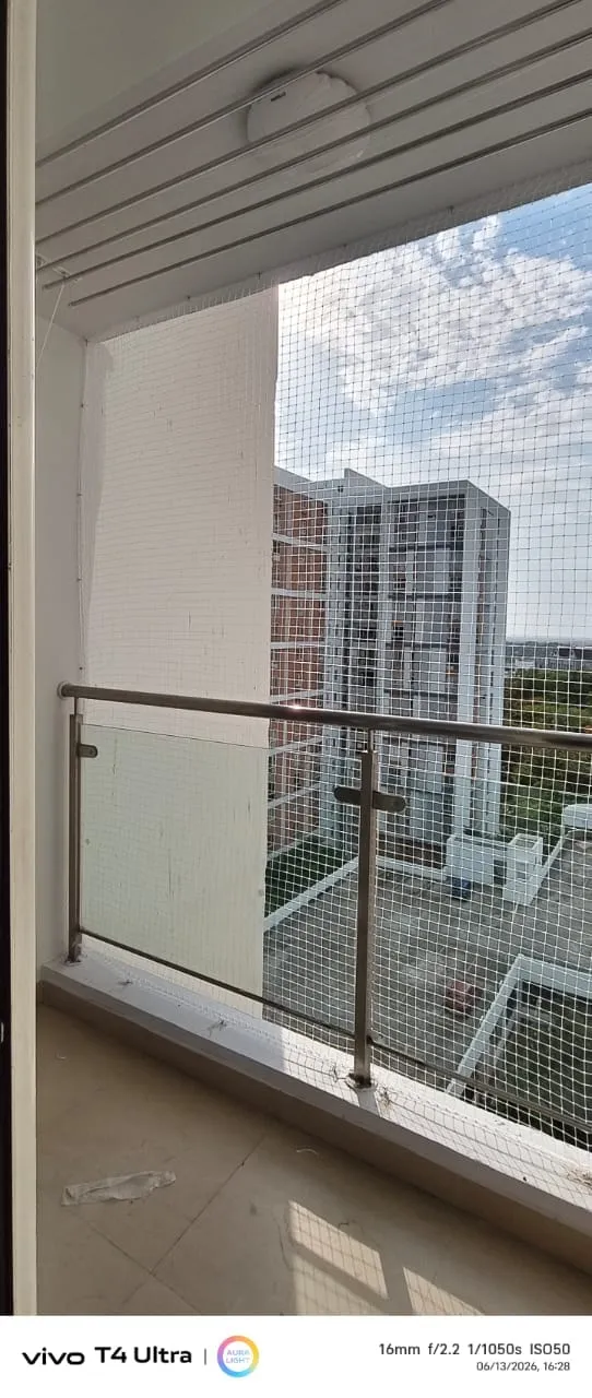Pigeon net covering a balcony with steel and glass railing on a high floor