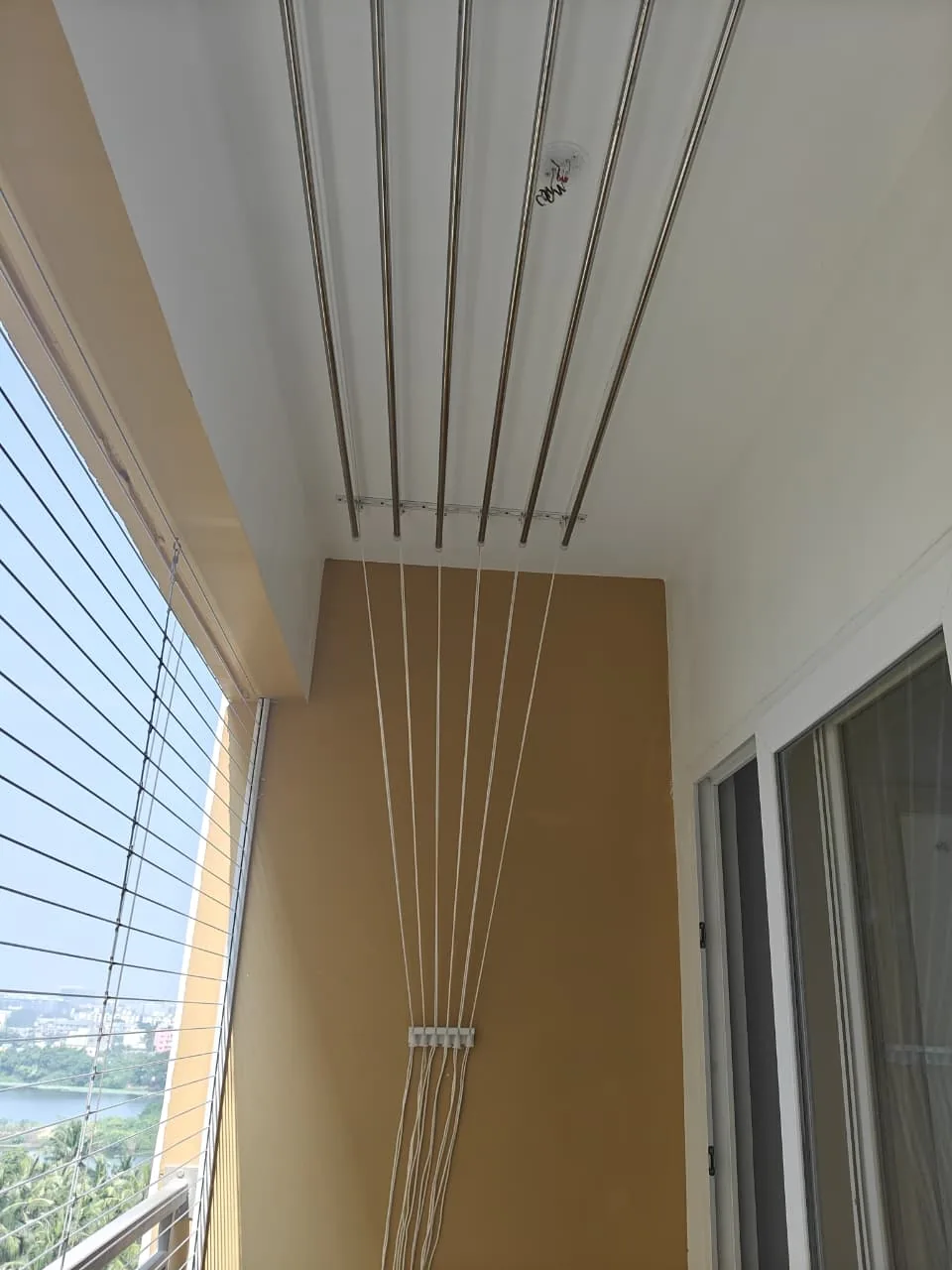 Balcony ceiling cloth hanger with wall cleat beside an invisible grill railing
