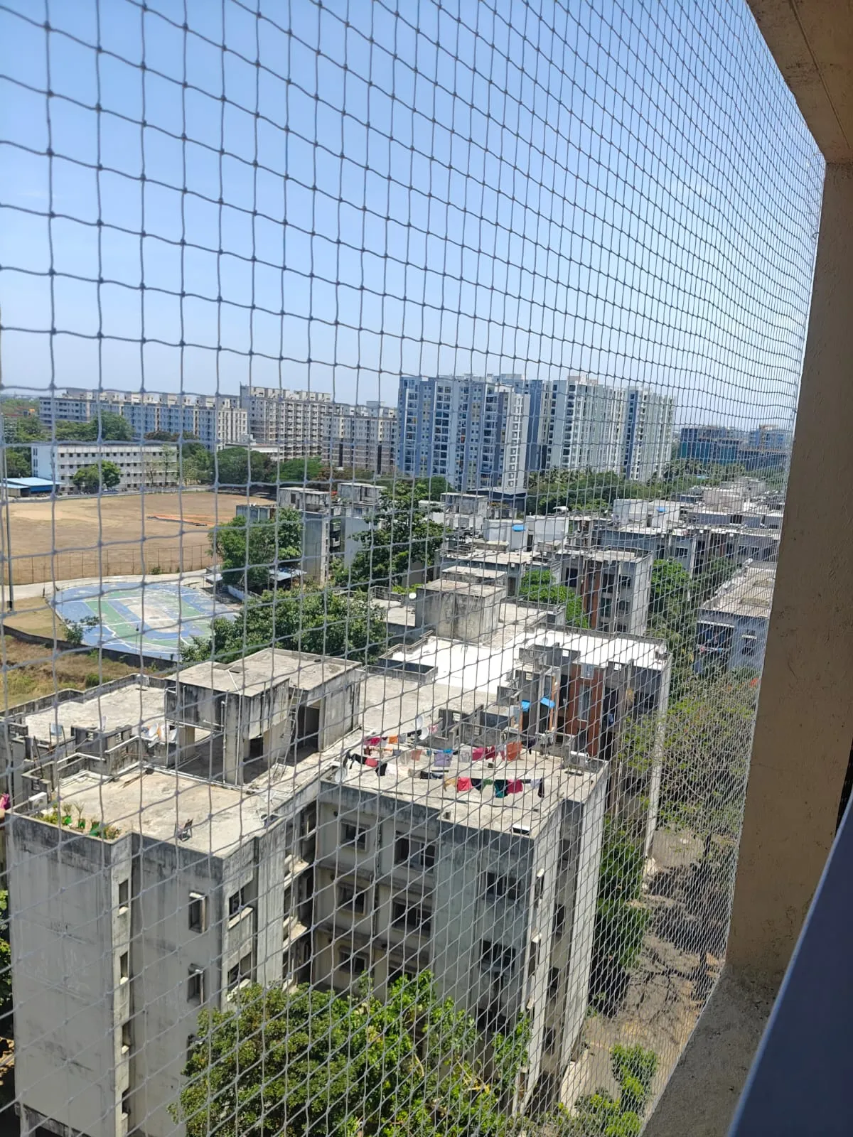 Bird net covering a high-floor balcony with a wide view over apartment blocks