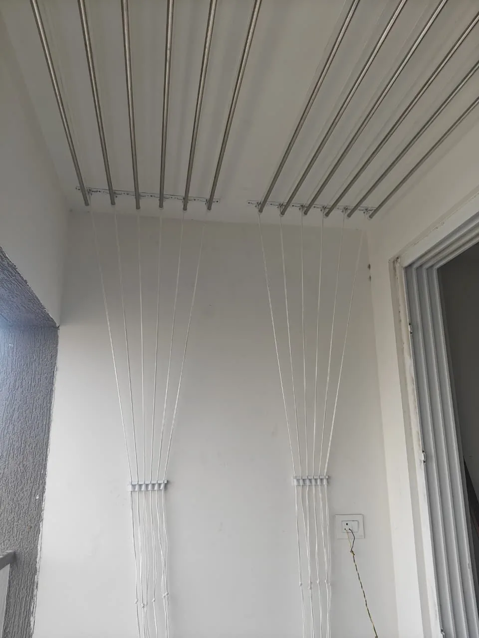 Wall-mounted pulley cloth hanger with rope cleat beside a utility window
