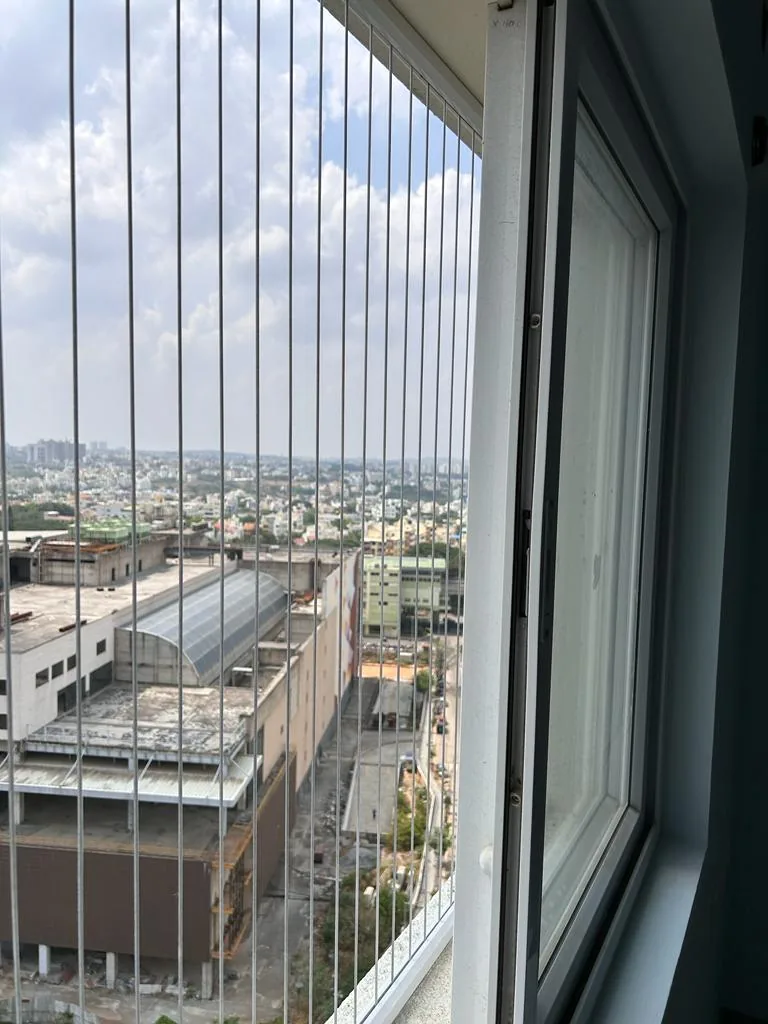 Close-up of invisible grill cables on a high-floor Bangalore apartment window