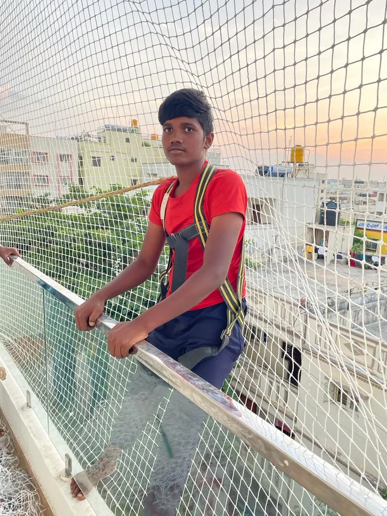 Installer in a safety harness fitting a balcony safety net at sunset